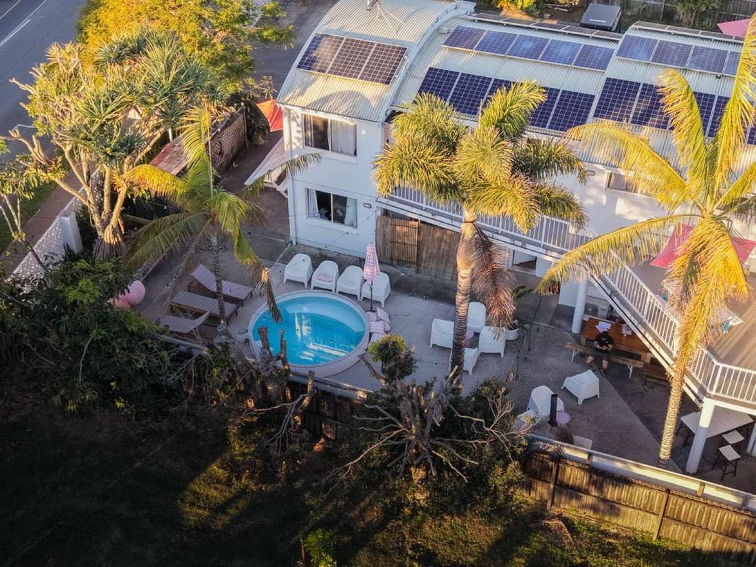 Golden-hour aerial of the CALI Backpackers plunge pool and palms