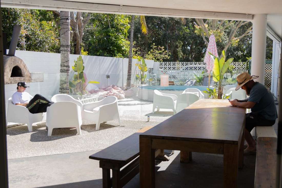 Guests hanging out on the deck by the pool at CALI Backpackers