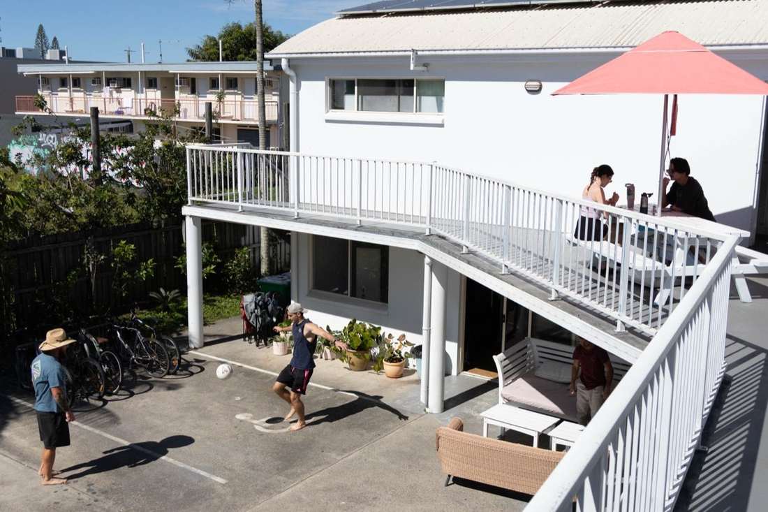 Guests playing football while others eat on the deck at CALI Backpackers